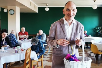 uśmiechnięty mieszkaniec z koszem wypełnionym papierowymi kwiatami